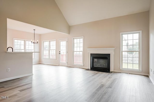 5933 Big Nance Dr, Raleigh, NC 27616 - unfurnished living room featuring a chandelier, wood finished floors, a fireplace with flush hearth, and high vaulted ceiling