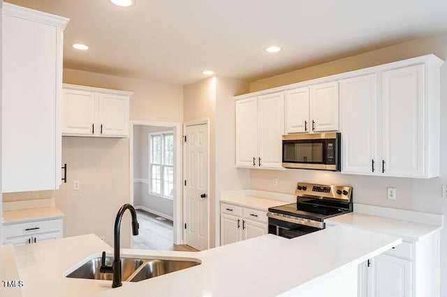 5933 Big Nance Dr, Raleigh, NC 27616 - kitchen featuring stainless steel appliances, white cabinets, recessed lighting, light countertops, and wood finished floors