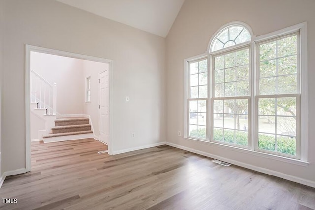 5933 Big Nance Dr, Raleigh, NC 27616 - empty room featuring healthy amount of natural light, wood finished floors, stairway, and vaulted ceiling