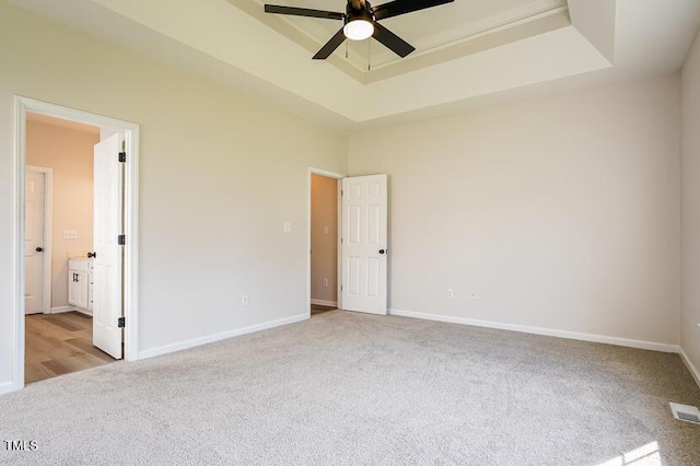 5933 Big Nance Dr, Raleigh, NC 27616 - unfurnished bedroom featuring carpet, a raised ceiling, connected bathroom, and a ceiling fan