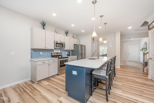 3922 Cross Timber Ln, Raleigh, NC 27603 - kitchen with appliances with stainless steel finishes, light wood-style floors, tasteful backsplash, a kitchen bar, and an island with sink