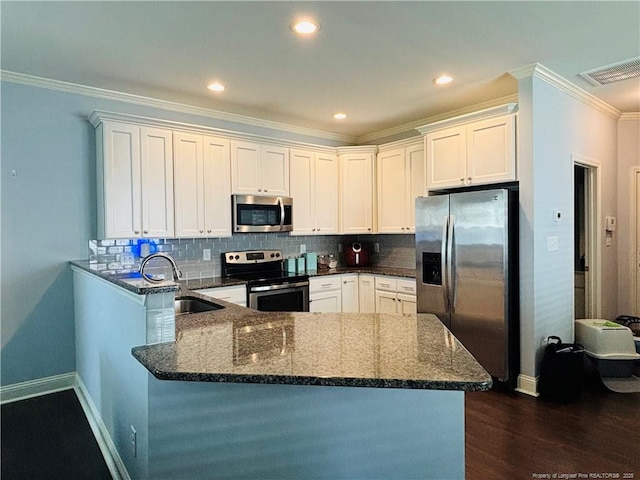 914 W Rowan St SW, Fayetteville, NC 28301 - kitchen with appliances with stainless steel finishes, a peninsula, ornamental molding, dark wood-style flooring, and dark stone countertops