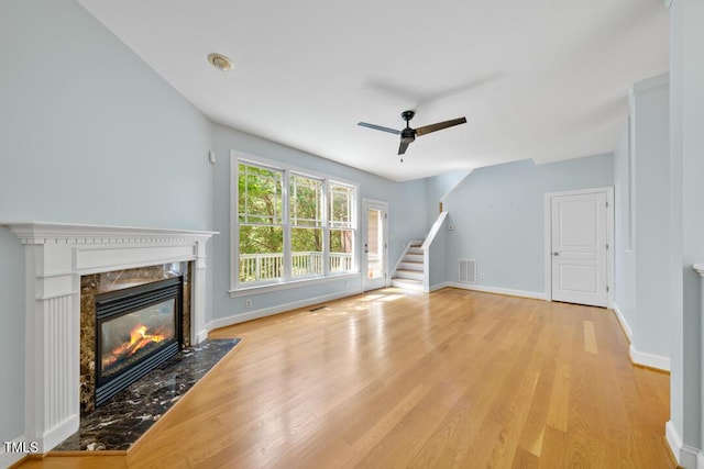 203 Bluefield Rd, Chapel Hill, NC 27517 - unfurnished living room featuring a fireplace, a ceiling fan, light wood finished floors, and stairs