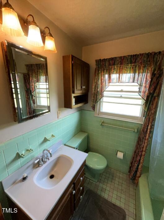 2035 Simpkins Rd, Raleigh, NC 27603 - full bathroom featuring tile walls, tile patterned flooring, healthy amount of natural light, vanity, and wainscoting