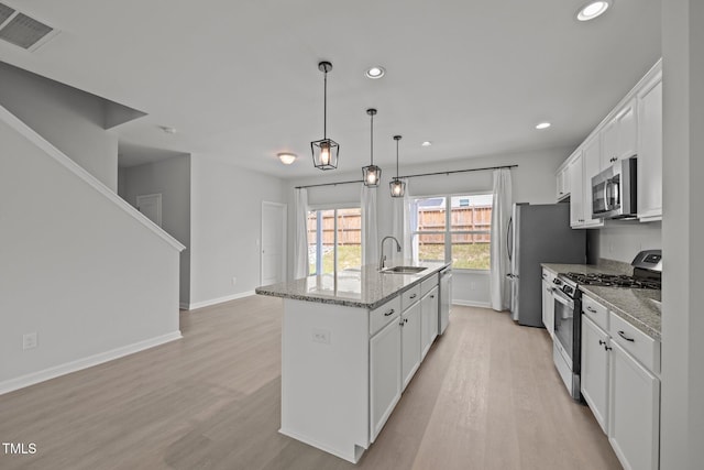 5404 Rutledgeville Ln, Knightdale, NC 27545 - kitchen with stainless steel appliances, light wood-style floors, white cabinets, a kitchen island with sink, and recessed lighting
