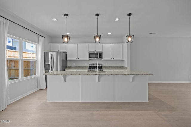 5404 Rutledgeville Ln, Knightdale, NC 27545 - kitchen with stainless steel microwave, recessed lighting, an island with sink, a kitchen breakfast bar, and white cabinetry
