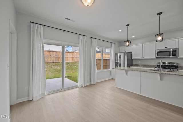 5404 Rutledgeville Ln, Knightdale, NC 27545 - kitchen with stainless steel appliances, a breakfast bar area, light wood-type flooring, light stone counters, and recessed lighting