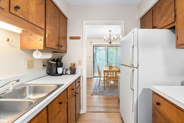 4316 American Dr, Durham, NC 27705 - kitchen with freestanding refrigerator, brown cabinetry, light countertops, light wood finished floors, and a chandelier