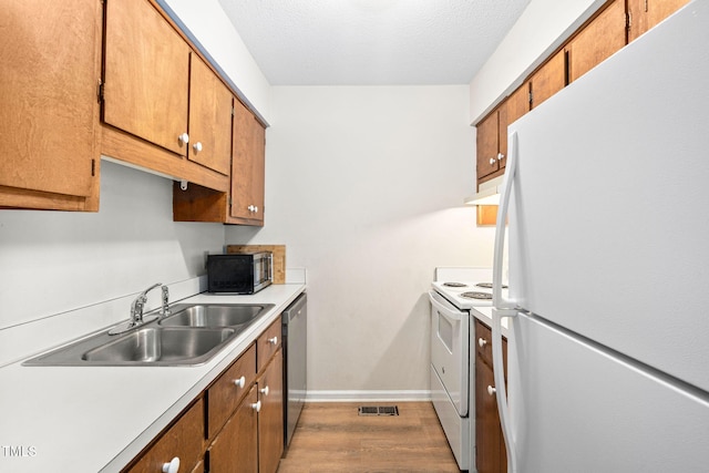 4316 American Dr, Durham, NC 27705 - kitchen featuring white appliances, light countertops, brown cabinets, wood finished floors, and a textured ceiling