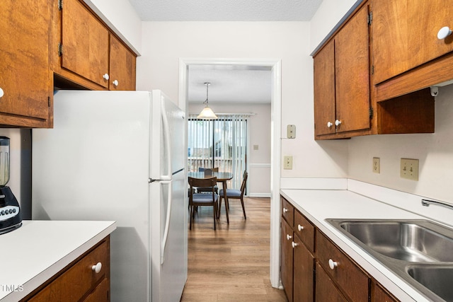 4316 American Dr, Durham, NC 27705 - kitchen featuring freestanding refrigerator, light countertops, light wood-type flooring, and brown cabinetry