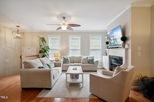 4104 Earl Grey Ct, Raleigh, NC 27612 - living room with wood finished floors, ornamental molding, a lit fireplace, ceiling fan, and a chandelier