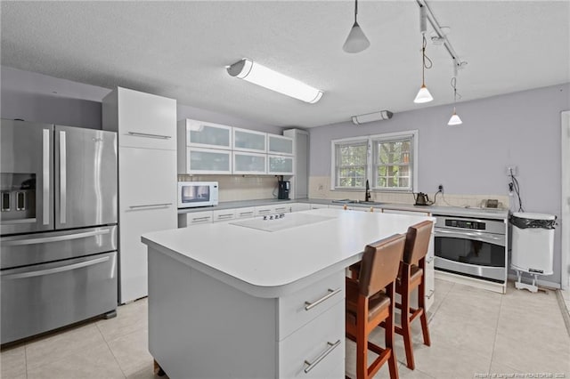 5945 Muscat Rd, Hope Mills, NC 28348 - kitchen with appliances with stainless steel finishes, light tile patterned floors, a breakfast bar area, and light countertops