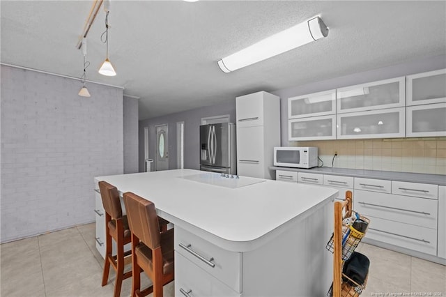 5945 Muscat Rd, Hope Mills, NC 28348 - kitchen with stainless steel fridge with ice dispenser, white microwave, a center island, light countertops, and glass insert cabinets