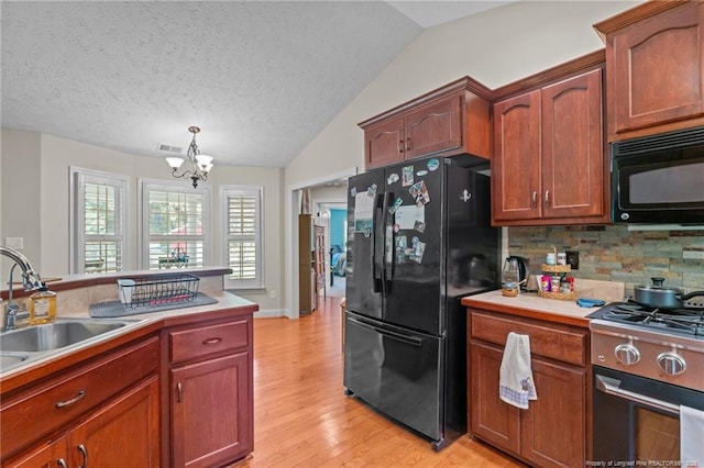 1438 Division Pl, Fayetteville, NC 28312 - kitchen featuring black appliances, a chandelier, light wood-type flooring, backsplash, and lofted ceiling