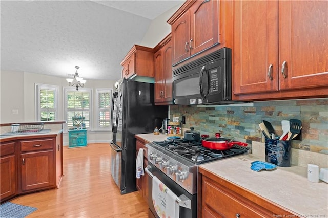 1438 Division Pl, Fayetteville, NC 28312 - kitchen featuring stainless steel gas range oven, black microwave, light wood finished floors, light countertops, and a chandelier
