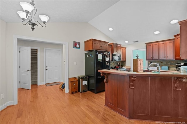 1438 Division Pl, Fayetteville, NC 28312 - kitchen featuring black appliances, a chandelier, decorative backsplash, a peninsula, and vaulted ceiling
