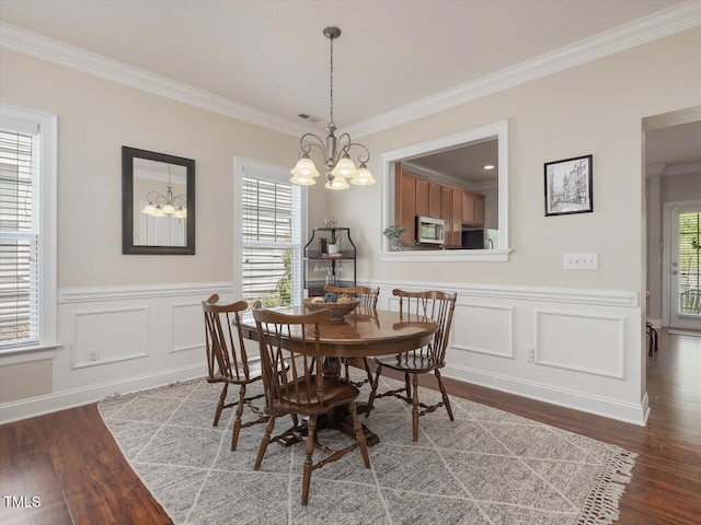 7712 Acc Blvd, Raleigh, NC 27617 - dining space featuring a chandelier, wood finished floors, crown molding, healthy amount of natural light, and a wainscoted wall