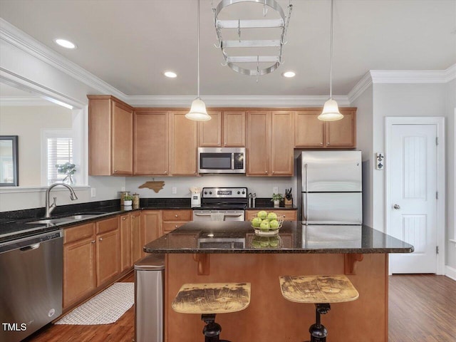 7712 Acc Blvd, Raleigh, NC 27617 - kitchen featuring appliances with stainless steel finishes, dark wood-type flooring, a center island, crown molding, and a breakfast bar area