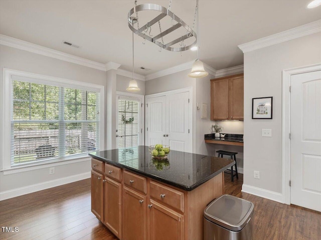 7712 Acc Blvd, Raleigh, NC 27617 - kitchen featuring dark wood-style flooring, ornamental molding, pendant lighting, a kitchen island, and dark stone countertops