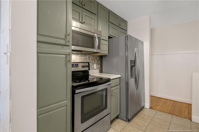 1828 Notre Dame Pl, Fayetteville, NC 28304 - kitchen featuring appliances with stainless steel finishes, green cabinetry, tasteful backsplash, light tile patterned floors, and light countertops