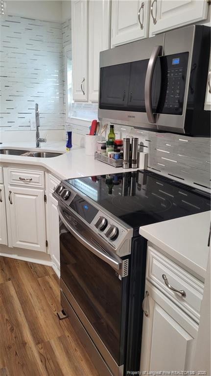 2508 N Roberts Ave N, Lumberton, NC 28358 - kitchen with electric range oven, stainless steel microwave, white cabinets, light wood-style flooring, and light countertops
