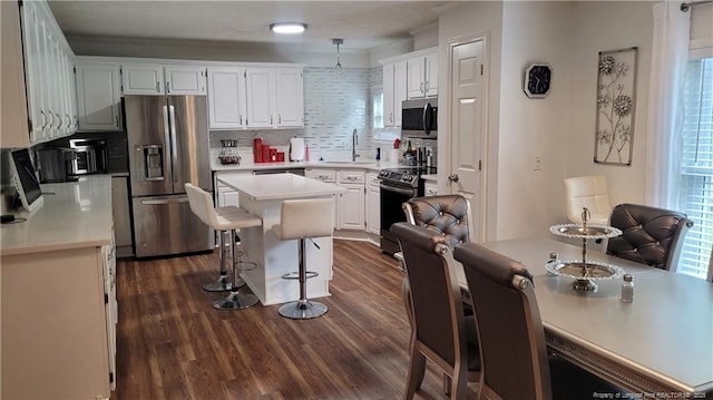 2508 N Roberts Ave N, Lumberton, NC 28358 - kitchen with appliances with stainless steel finishes, light countertops, dark wood-type flooring, a kitchen breakfast bar, and ornamental molding