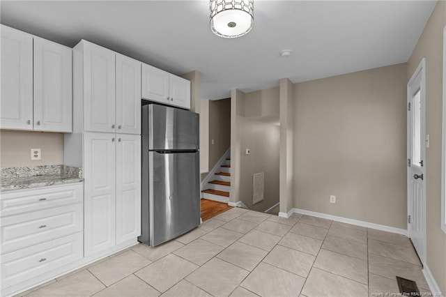 521 Fawn Ct, Fayetteville, NC 28303 - kitchen with freestanding refrigerator, white cabinetry, light tile patterned floors, and light stone countertops