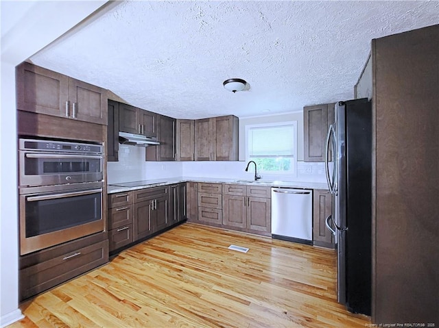 7246 Faircloth Bridge Rd, Stedman, NC 28391 - kitchen with stainless steel appliances, light wood-style flooring, light countertops, dark brown cabinetry, and a textured ceiling