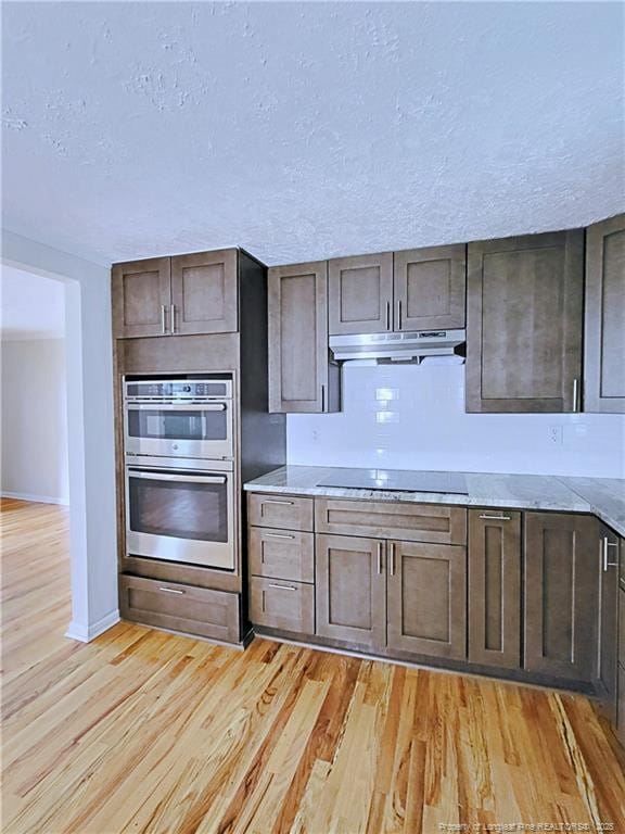 7246 Faircloth Bridge Rd, Stedman, NC 28391 - kitchen featuring double oven, under cabinet range hood, black electric stovetop, light wood finished floors, and a textured ceiling