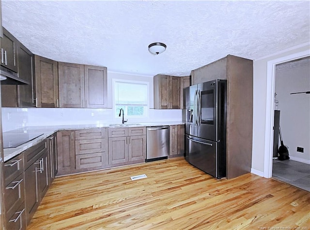 7246 Faircloth Bridge Rd, Stedman, NC 28391 - kitchen with stainless steel appliances, light wood finished floors, a textured ceiling, dark brown cabinets, and light stone countertops
