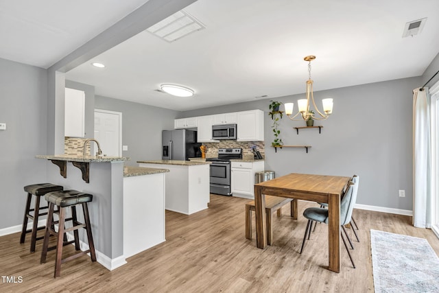 2127 Rivergrass Ct, Raleigh, NC 27610 - kitchen featuring stainless steel appliances, backsplash, a peninsula, a chandelier, and white cabinets