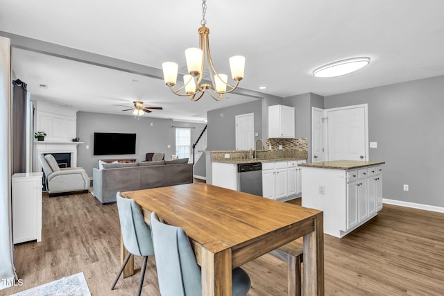 2127 Rivergrass Ct, Raleigh, NC 27610 - dining space featuring ceiling fan, light wood-type flooring, a large fireplace, a chandelier, and recessed lighting