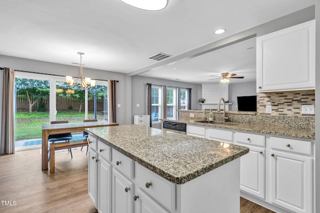 2127 Rivergrass Ct, Raleigh, NC 27610 - kitchen with dishwasher, a chandelier, a center island, backsplash, and light stone countertops
