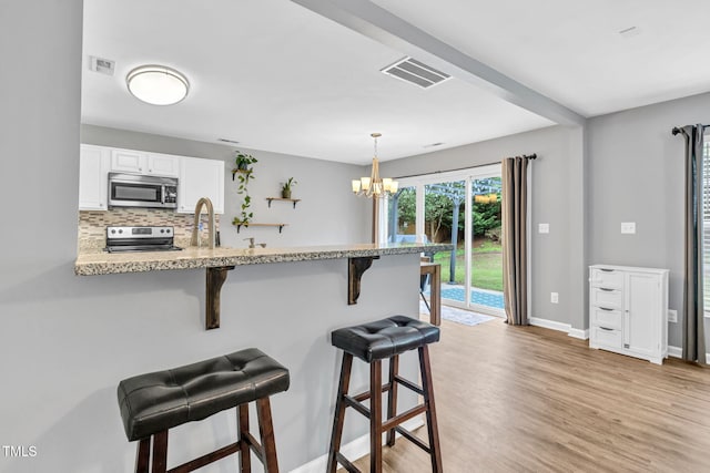 2127 Rivergrass Ct, Raleigh, NC 27610 - kitchen featuring stainless steel appliances, a breakfast bar, white cabinetry, a peninsula, and a chandelier