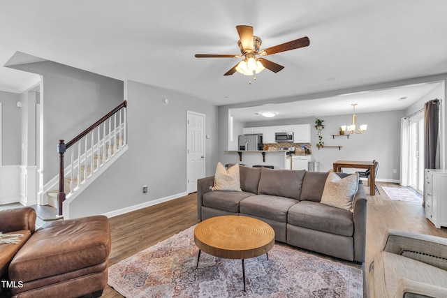 2127 Rivergrass Ct, Raleigh, NC 27610 - living room with wood finished floors, a chandelier, ceiling fan, and stairway