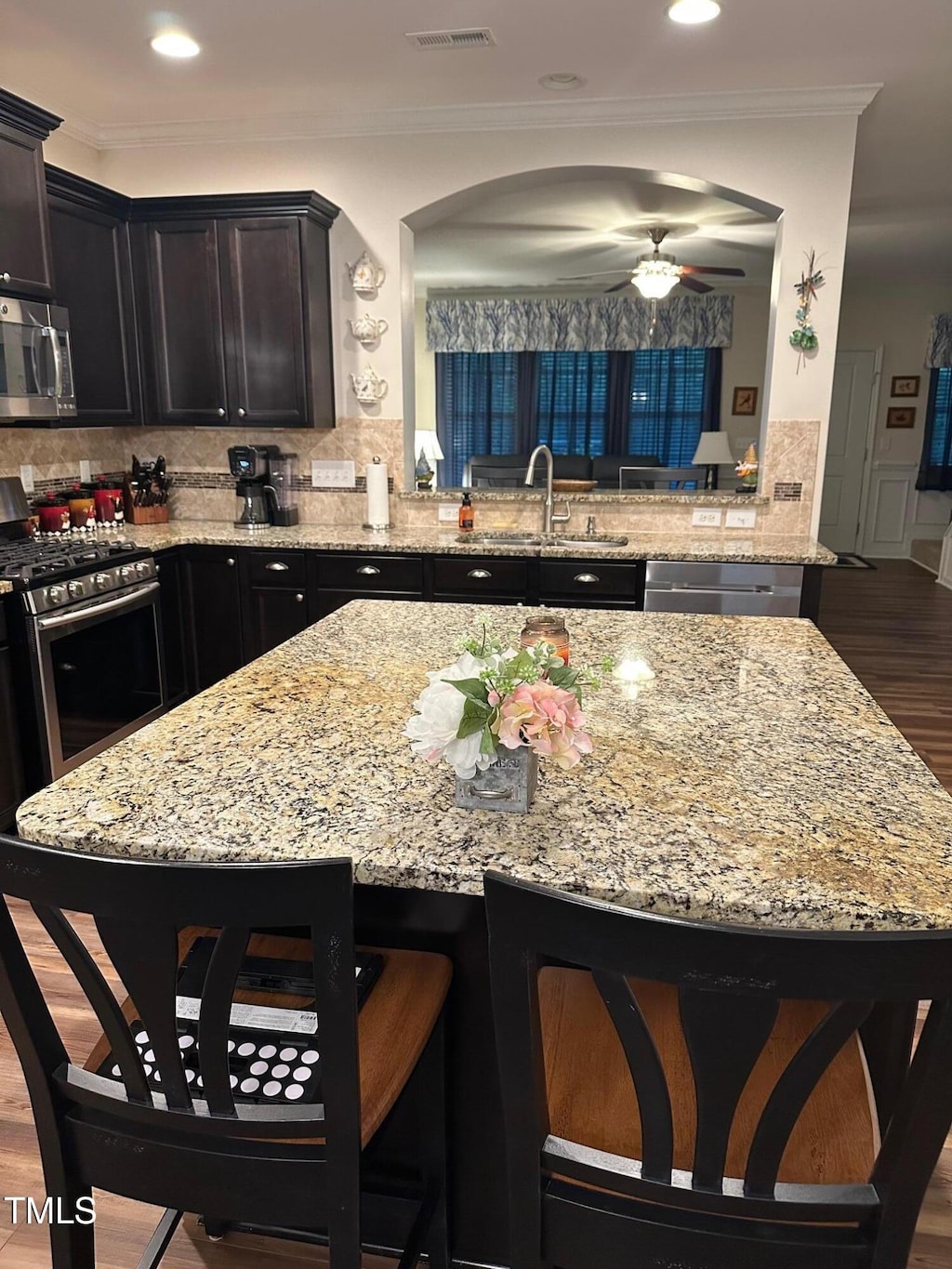 6004 Stony Falls Way, Knightdale, NC 27545 - kitchen with appliances with stainless steel finishes, a breakfast bar, light stone countertops, backsplash, and ornamental molding