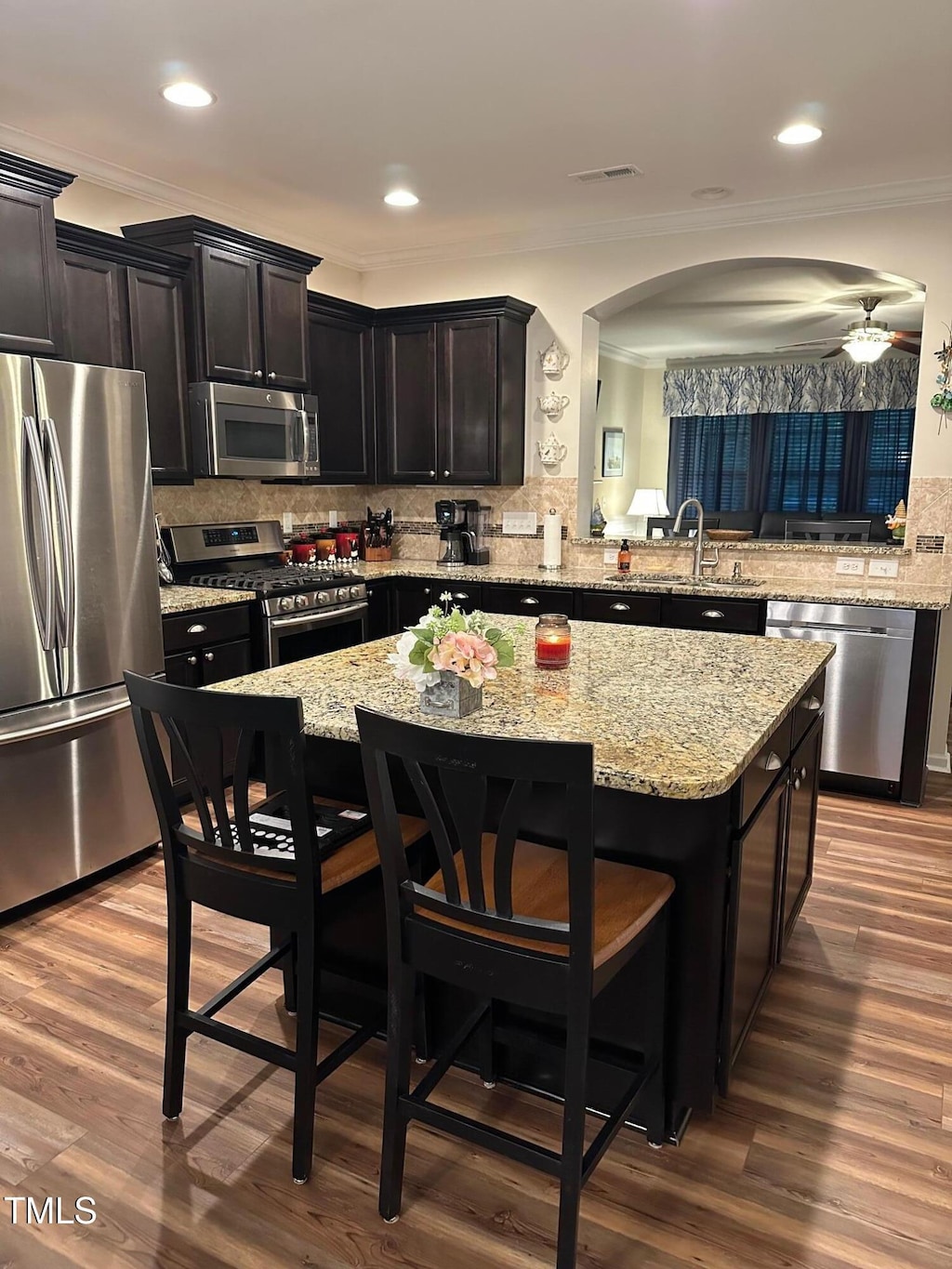 6004 Stony Falls Way, Knightdale, NC 27545 - kitchen with stainless steel appliances, ornamental molding, a kitchen island, tasteful backsplash, and a breakfast bar