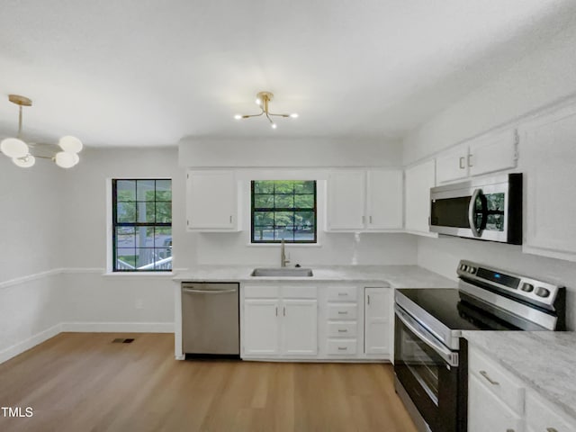 11 Sweetbay Ct, Durham, NC 27704 - kitchen featuring appliances with stainless steel finishes, light wood-style floors, white cabinets, and light countertops