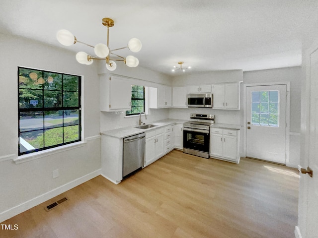 11 Sweetbay Ct, Durham, NC 27704 - kitchen with stainless steel appliances, light wood-type flooring, white cabinets, and light countertops