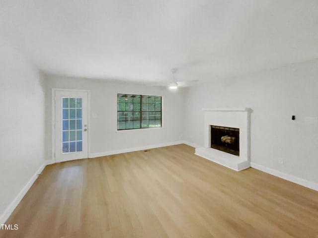 11 Sweetbay Ct, Durham, NC 27704 - unfurnished living room with light wood-type flooring, ceiling fan, and a fireplace