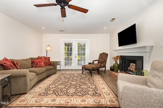 1520 Woodcroft Dr, Raleigh, NC 27609 - living room featuring wood finished floors, french doors, ceiling fan, a fireplace with raised hearth, and recessed lighting
