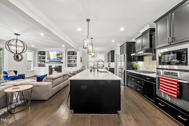 7741 Wilderness Rd, Raleigh, NC 27613 - kitchen with appliances with stainless steel finishes, open floor plan, dark cabinetry, a chandelier, and light countertops