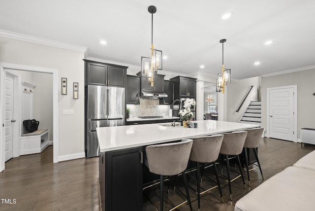 7741 Wilderness Rd, Raleigh, NC 27613 - kitchen featuring freestanding refrigerator, light countertops, decorative backsplash, a center island with sink, and crown molding