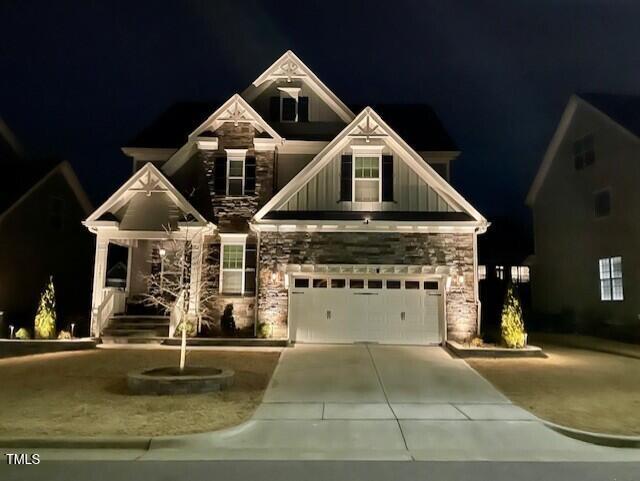 7741 Wilderness Rd, Raleigh, NC 27613 - craftsman-style home with board and batten siding, stone siding, concrete driveway, and a garage