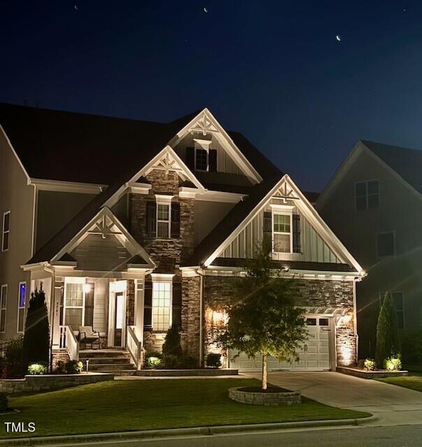 7741 Wilderness Rd, Raleigh, NC 27613 - craftsman-style home featuring stone siding, driveway, a lawn, and covered porch