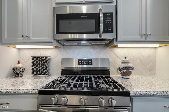 2461 Patriot Bluffs Dr, Fuquay Varina, NC 27526 - kitchen with stainless steel appliances, tasteful backsplash, light stone counters, and gray cabinets