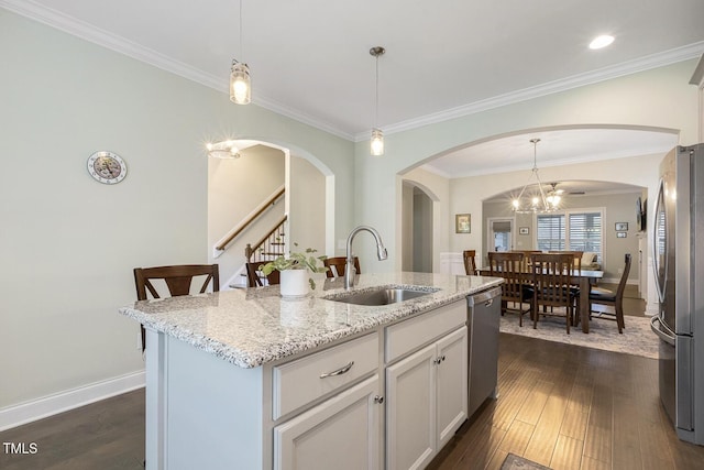 2461 Patriot Bluffs Dr, Fuquay Varina, NC 27526 - kitchen with stainless steel appliances, arched walkways, dark wood-style floors, light stone countertops, and ornamental molding