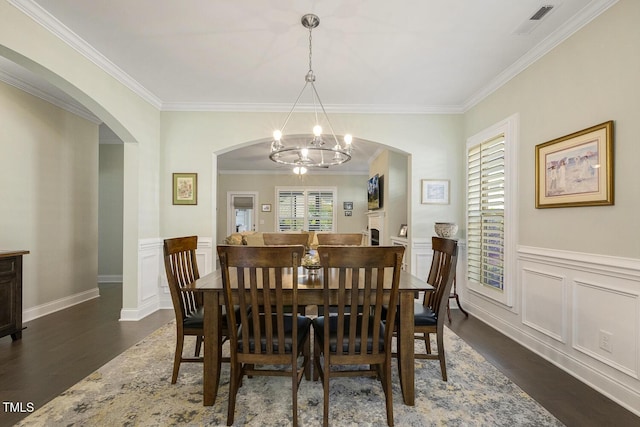 2461 Patriot Bluffs Dr, Fuquay Varina, NC 27526 - dining area with a chandelier, dark wood-style flooring, crown molding, arched walkways, and wainscoting