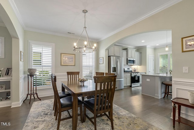 2461 Patriot Bluffs Dr, Fuquay Varina, NC 27526 - dining space featuring arched walkways, a chandelier, dark wood-type flooring, crown molding, and a wainscoted wall