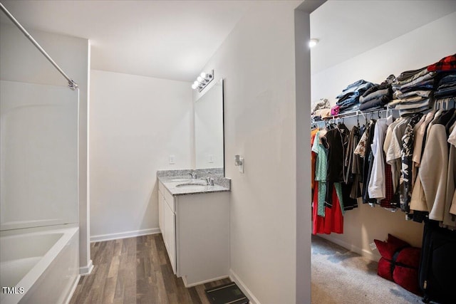 443 Waterfall Rd, Henderson, NC 27537 - bathroom with vanity, washtub / shower combination, a spacious closet, and wood finished floors